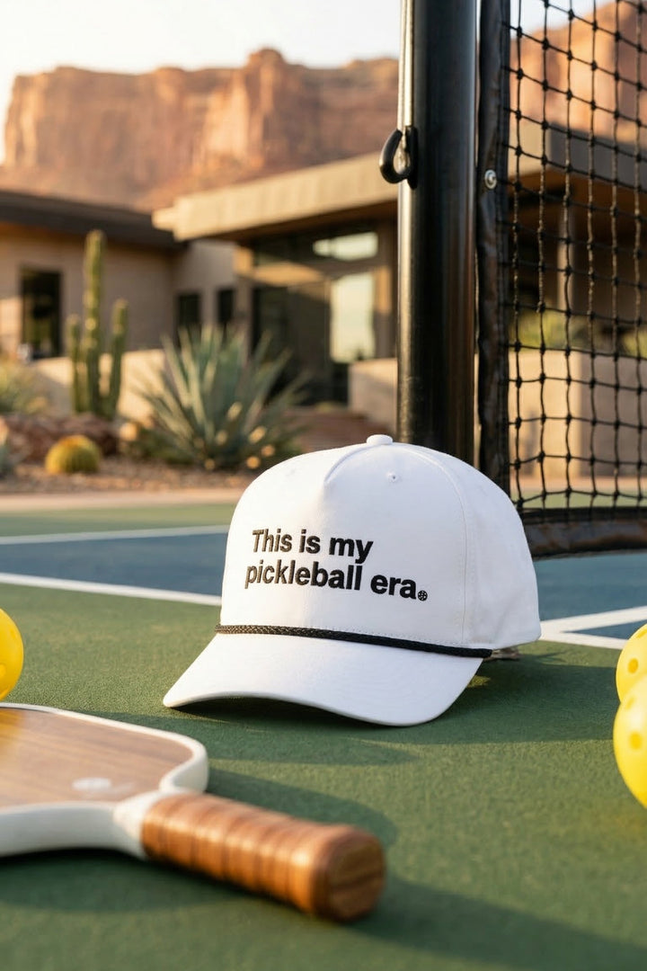 Pickleball cap with text on a court with a scenic background